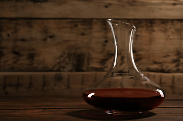 Elegant decanter with red wine on wooden table