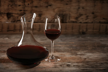Elegant decanter and glass with red wine on wooden table