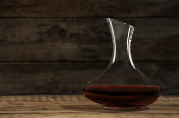 Elegant decanter with red wine on wooden table