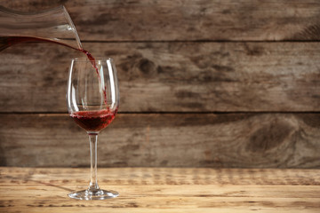 Pouring delicious red wine into glass on table