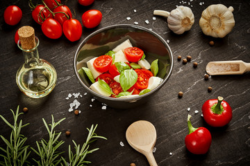 delicious salad with cherry tomatoes mozzarella and basil in a bowl on a black wooden table