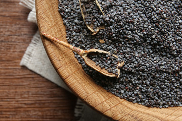 Plate with poppy seeds on wooden table, top view