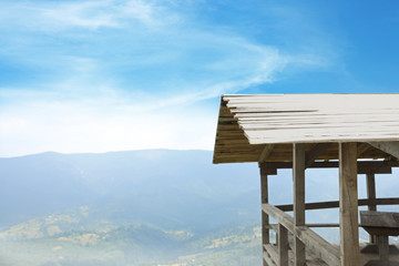 Picturesque landscape with wooden gazebo and mountain forest on background