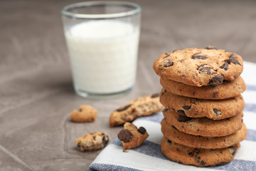 Tasty cookies with chocolate chips and glass of milk on grey table
