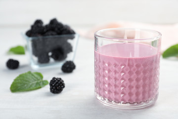 Glass with tasty blackberry yogurt smoothie on table
