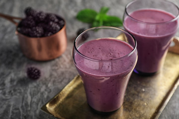 Glasses with tasty blackberry yogurt smoothies on grey table
