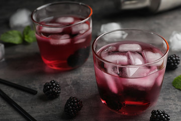 Glasses with iced blackberry lemonade on grey table