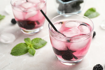 Glasses with iced blackberry lemonade on table