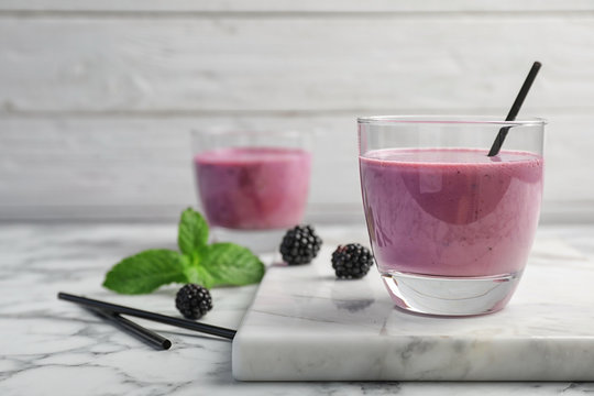 Glass with tasty blackberry yogurt smoothie on table