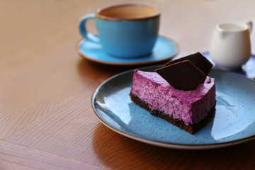 Plate with slice of berry cheesecake on wooden table