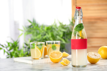 Bottle with natural lemonade on table against blurred background