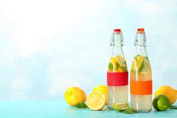 Bottles with natural lemonade on table against color background