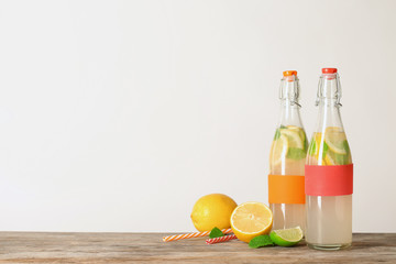 Bottles with natural lemonade on table against white background