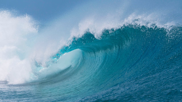 CLOSE UP: Beautiful deep blue tube wave in the Pacific curls on a sunny day.