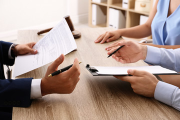 Lawyer working with clients at table in office, focus on hands