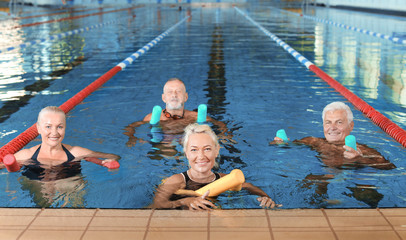 Sportive senior people doing exercises in indoor swimming pool