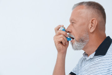 Man using asthma inhaler on white background