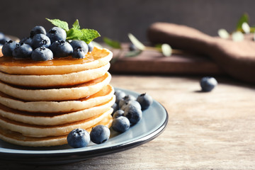 Plate with pancakes and berries on wooden table