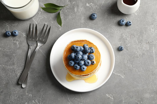 Plate with pancakes and berries on grey background, top view