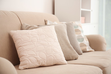 Different soft pillows on sofa in room