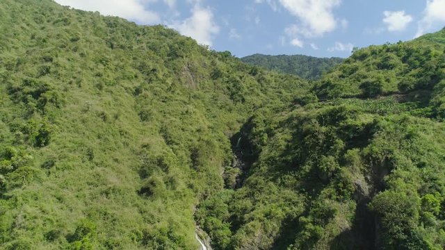 Aerial view of waterfall in the mountains of Filipino cordillera. Waterfall in the mountains. waterfall flowing on the slopes of mountains covered with tropical vegetation. Philippines, Luzon