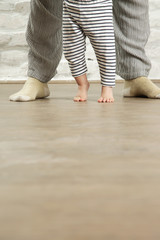 Mother teaching baby to walk, indoor candid photo