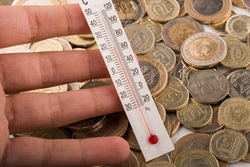 Thermometer in hand beside Turkish Lira coins