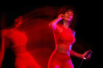 Naklejka premium Happy young and fitness woman dancing on black background