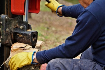 A man working with the firewood to split the logs by the machine on the driveway in the garden, Winter in GA USA.