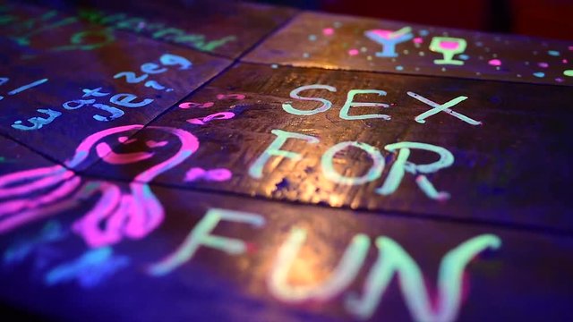 Painted Bar desk with inscription sex for fun by fluorescent pain during night.