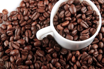 Mug full of, and surrounded by, coffee beans