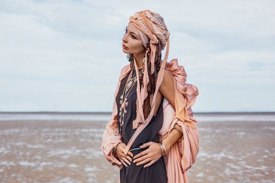 young stylish woman with fashionable boho accessories on the beach windy time