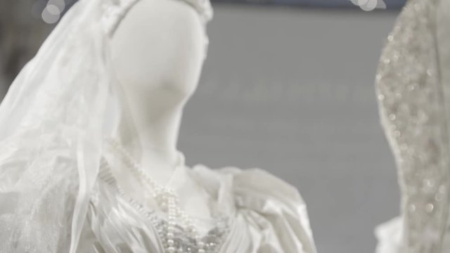 A white lacy dress on a female mannequin. Dettail of a wedding gown with necklace made of pearls. Fashion concept.