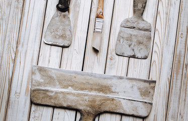Kit of putty knives. Spatulas with the remaining mortar. Gastarbeiter or guest worker concept....