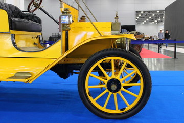 Fragment of a old yellow vintage car on a blue background at the exhibition