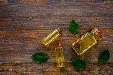 Tea tree essential oil near tea tree leaves on dark wooden background top view copy space