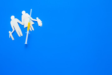 Vaccination for healthy family, vacctination of children. Flu. Syringe near family cutout on blue background top view copy space