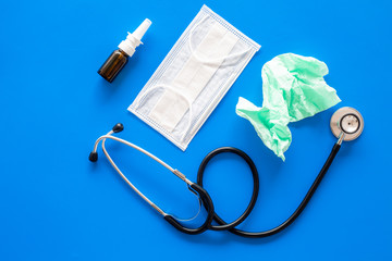Flu drops. Running nose concept. Wrinkled napkin near stethoscope and face mask on blue background top view copy space