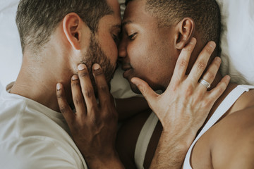 Gay couple cuddling in bed - obrazy, fototapety, plakaty