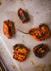 Grouping of oven roasted habaneros on a baking tray that have been cut open.