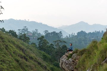 Woman sitting on the top of Small Adams peak near Ella, Sri Lanka