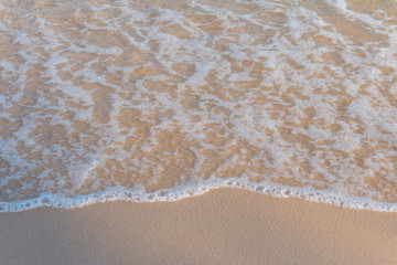 Sea beach foam from surf with light brown sand beach