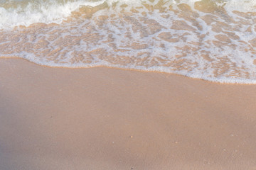 Sea beach foam from surf with light brown sand beach