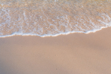 Fototapeta na wymiar Sea beach foam from surf with light brown sand beach