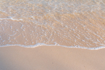 Fototapeta na wymiar Sea beach foam from surf with light brown sand beach