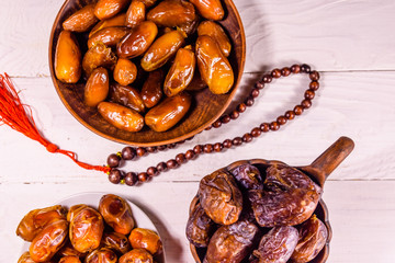 Date fruits and rosary on wooden table. Top view