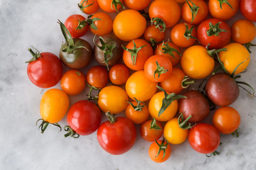 Freshly picked heirloom tomatoes, yellow, red, and purple, on a gray marble slab, black background
