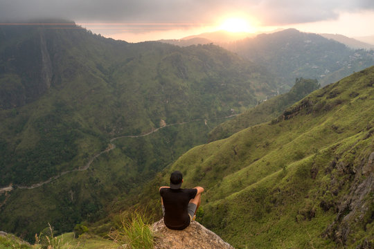 Man sitting on the top of Small Adams peak watching sunset. Ella, Sri Lanka