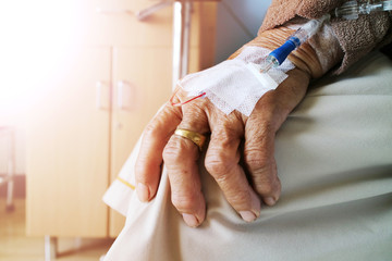 The old woman with saline solution in hospital. Grandmother resting at hospital bed with...