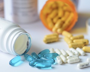 pills spilling out of pill bottle on white background